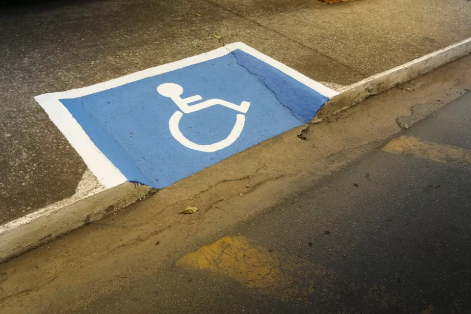 Sidewalk curb cut painted with blue and white disability symbol